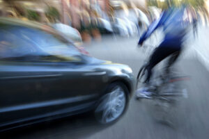 Dangerous city traffic situation with a cyclist and cars in motion blur