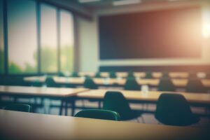 Blurred school classroom without students with empty chairs and tables. 