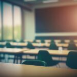 Blurred school classroom without students with empty chairs and tables. 