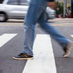 blurred pedestrian walking through a crosswalk on a city street