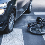 Car standing on the pedestrian path with the downed bicycle