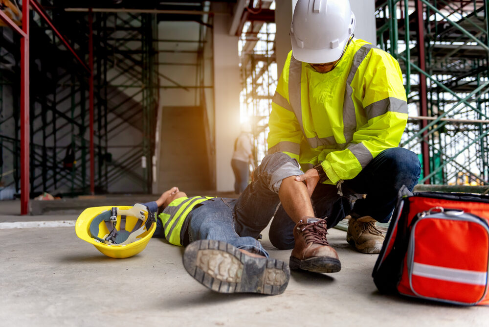 first aid being administered to a coworker at a construction site after an accident