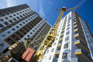 Building crane and building under construction against cloudy sky.