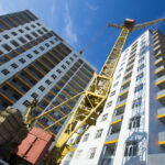 Building crane and building under construction against cloudy sky.