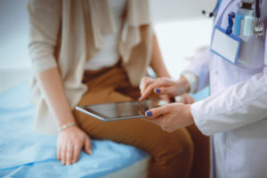 A doctor and patient talk while looking at a tablet