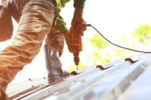 worker drilling down roofing tiles