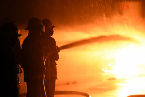 a group of firefighters spraying a factory fire