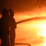 a group of firefighters spraying a factory fire