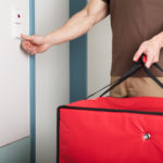 A man holding an insulated food delivery bag rings the doorbell