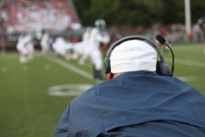 a high school football coach watching a game from the sideline.