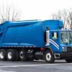 view of blue garbage truck on roadway