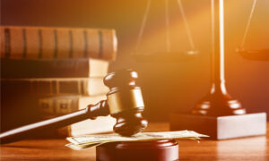 law books and scales of justice behind a gavel  on money at desk with soft filter