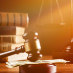 law books and scales of justice behind a gavel  on money at desk with soft filter