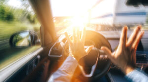 first person view from interior of a car as driver takes hands off of the wheel before an accident