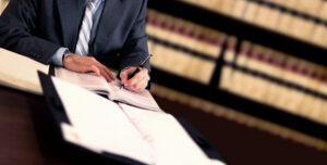 lawyer working at desk with law books behind