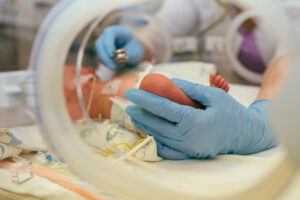newborn baby in intensive care unit in a incubator with a nurse taking vitals