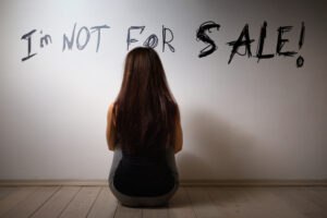 a young woman sitting in front of a white wall that reads" I'm not for sale!"