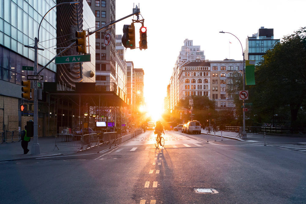 Person riding a bicycle into the sunset on 14th Street at Union Square in Manhattan, New York City NYC