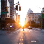 Person riding a bicycle into the sunset on 14th Street at Union Square in Manhattan, New York City NYC