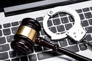 A gavel and handcuffs on a laptop keyboard