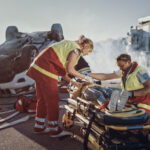 paramedics assisting a young woman on a stretcher at an overturned vehicle accident scene