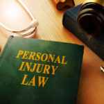 A book titled "PERSONAL INJURY LAW" sits on a desk with a gavel and stethoscope