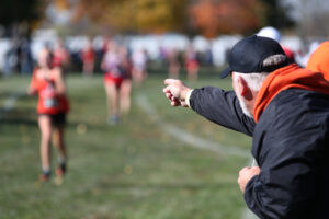 an older man pointing at girls cross country race