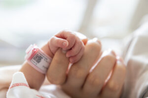 a premature baby holds on to mother's finger closeup