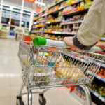 A shopping cart being pushed down a grocery aisle by an unseen person