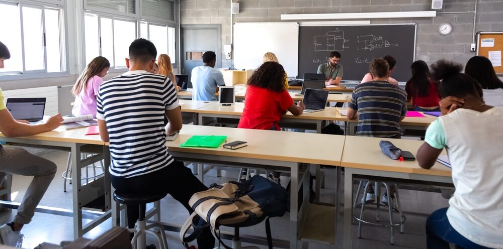 Rear view of group of multiracial high school students in class