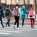 young school children walking across street at crosswalk