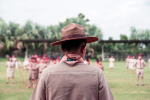 A scout leader looks out over a field of uniformed children