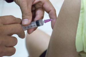 Close-up of a syringe injecting a vaccine into a patient's arm