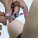 Close-up of a syringe injecting a vaccine into a patient's arm