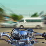 blurred image of a motorcycle heading towards vehicles.