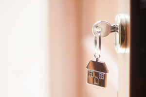 A key with a house-shaped keychain inserted into a lock