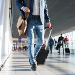 A man pulls his wheeled luggage through an airport terminal