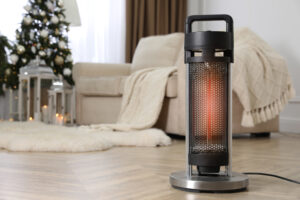 a modern space heater on the floor in living room with couches and christmas tree in the background