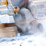 A construction worker using an electric handsaw to cut marble tiles