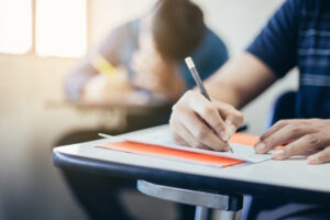 male high school student at desk taking a test with pencil in hand