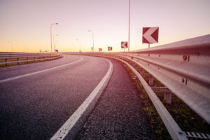 sunrise by a curved highway with guardrails