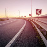 sunrise by a curved highway with guardrails