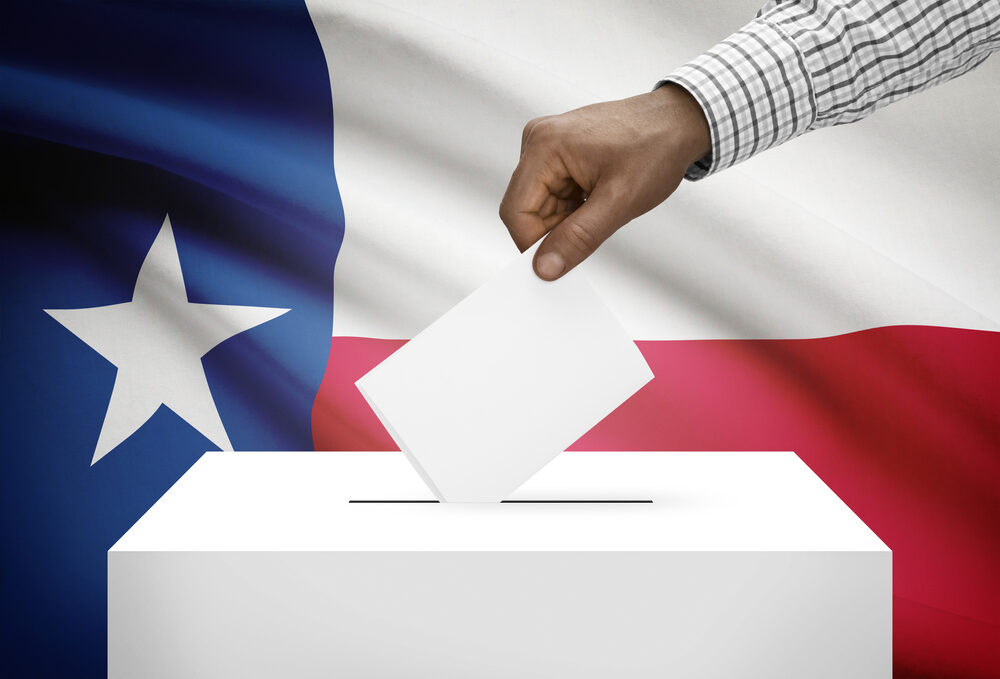 hand placing voting card into ballot box with Texas flag background