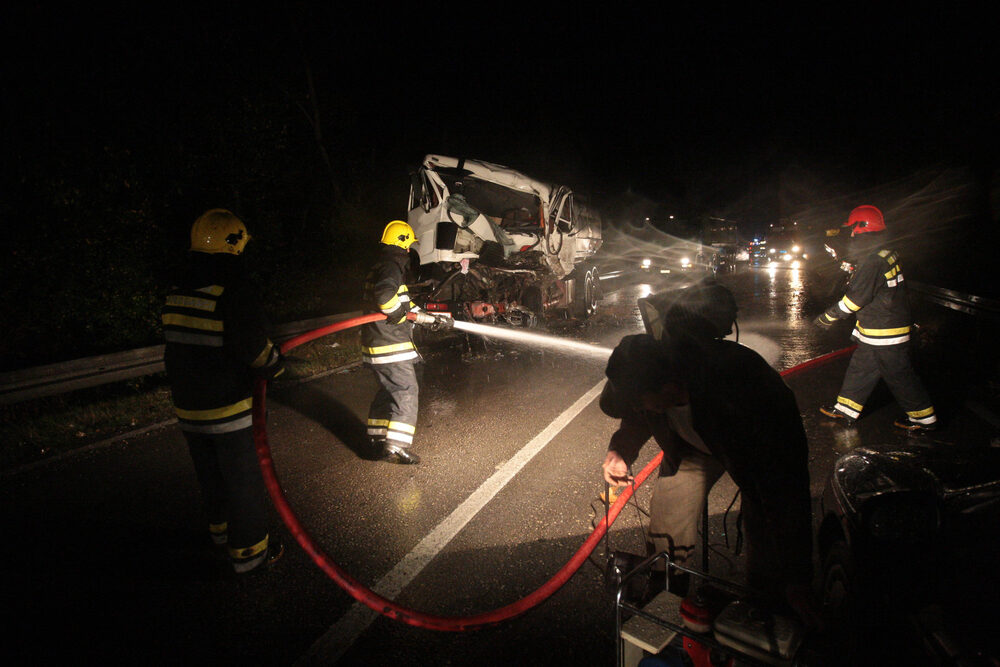 firemen spraying off the highway after a truck accident at night