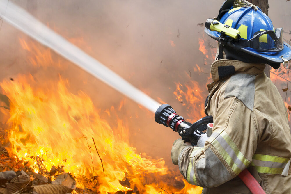 firefighter battling a wildfire with hose