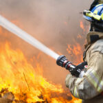 firefighter battling a wildfire with hose