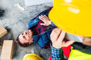 coworker calling for help while checking on injured worker down on the ground at jobsite