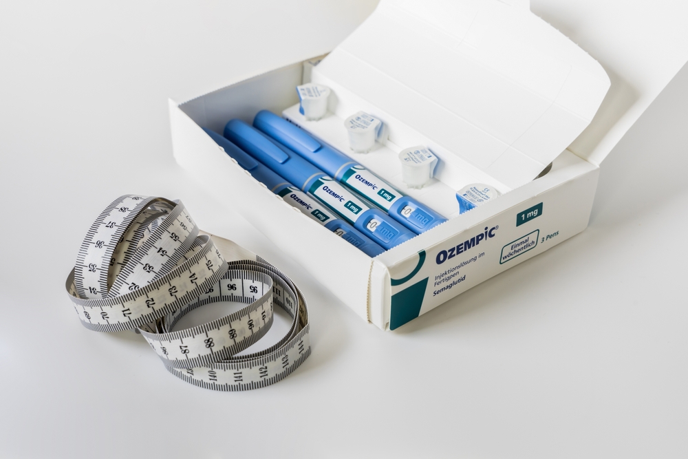 a box of ozempic injectors with cartridges on a white table with a measuring tape