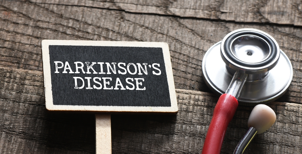 PARKINSON'S DISEASE words on a small chalk board next to a stethoscope on a wooden table.