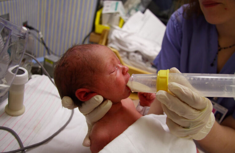 Premature newborn being fed formula from a nurse in hospital